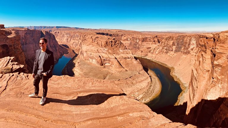 a man poses for a photo at the edge of Horseshoe Bend