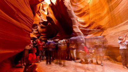 visitors on an Antelope Canyon tour stand between the stunning slot canyon walls