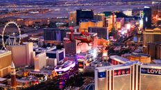 A helicopter in flight over the brightly lit Las Vegas Strip at night.