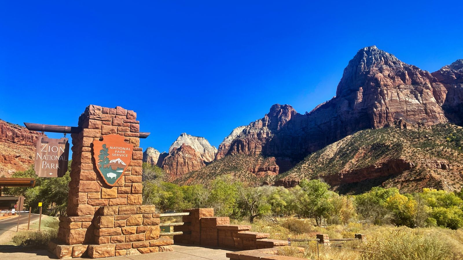 Zion National Park sign with the canyon landscape in the distance