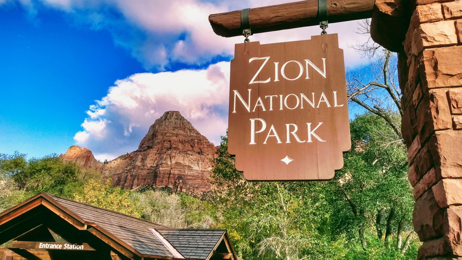 the entrance sign to Zion National Park with a canyon landscape in the background