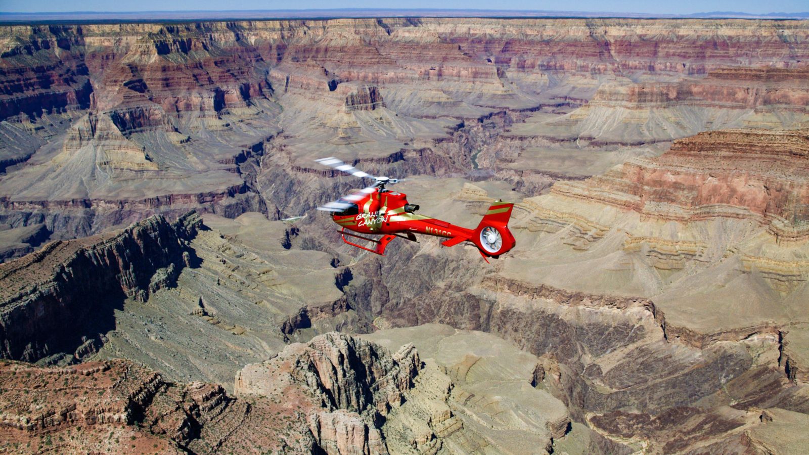 a red helicopter soars over the r9ock gorges of the grand canyon south rim