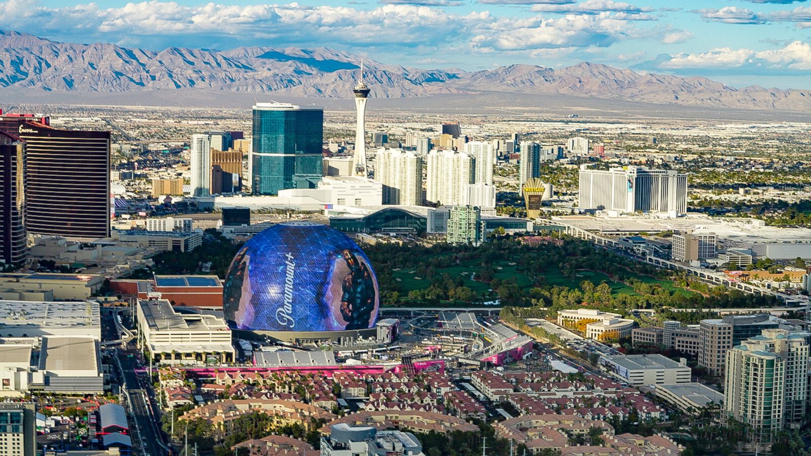 the Las Vegas Strip seen from above on a helicopter tour with the MSG Sphere in the forefront and other casinos and mountains in the background
