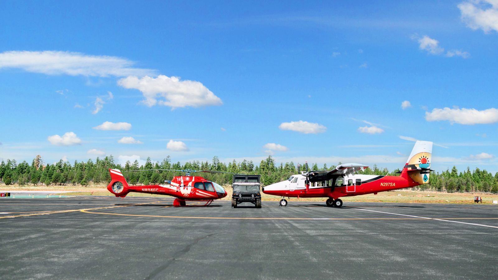 A sightseeing helicopter, an airplane, and a Hummer vehicle parked at the Grand Canyon South Rim