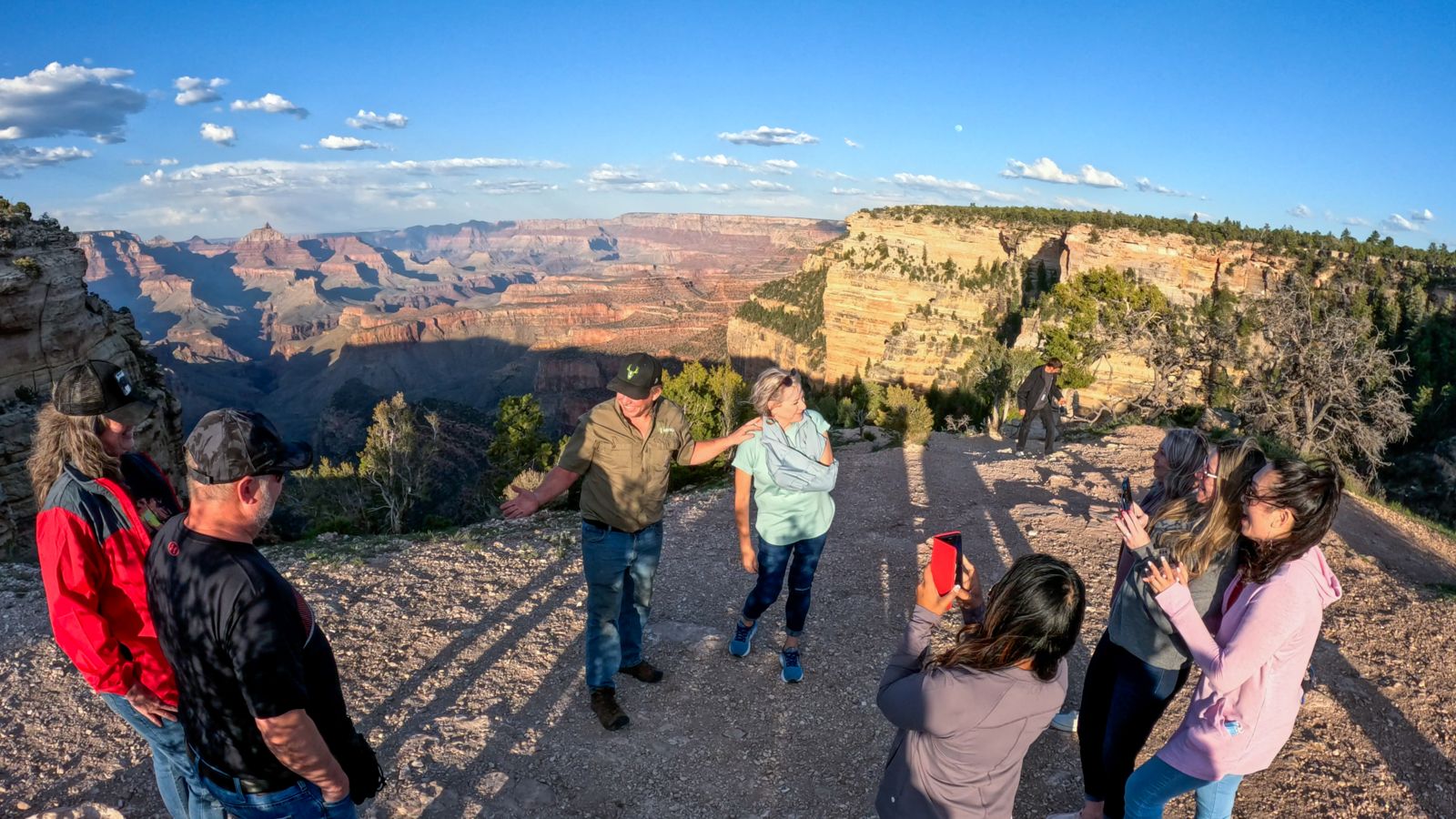Passengers aboard a Grand Canyon Hummer tour stand at the edge of a stunning lookout point