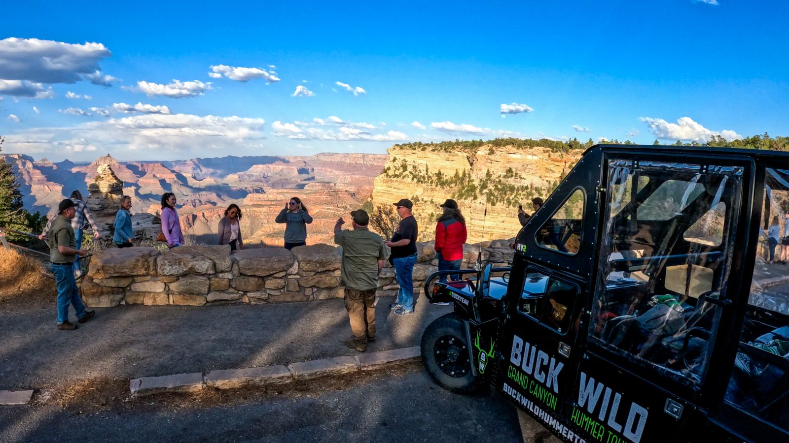 Passengers aboard a Grand Canyon Hummer tour stand at the famous Duck on a Rock lookout point