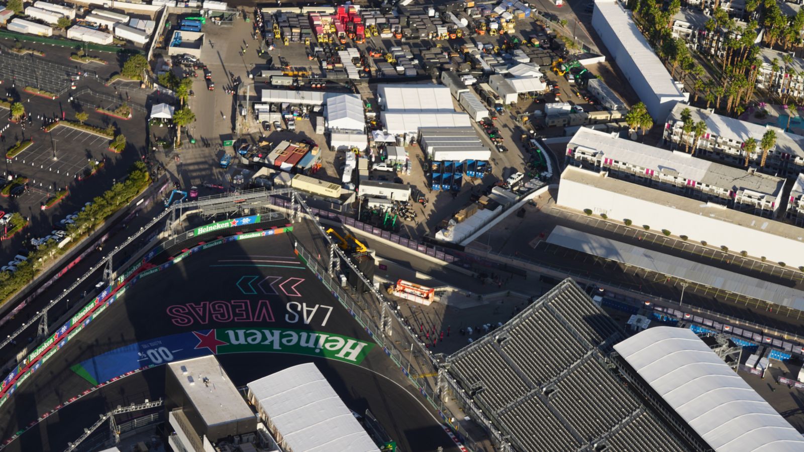 a sharp turn on the las vegas race track with grandstands and team garages in view