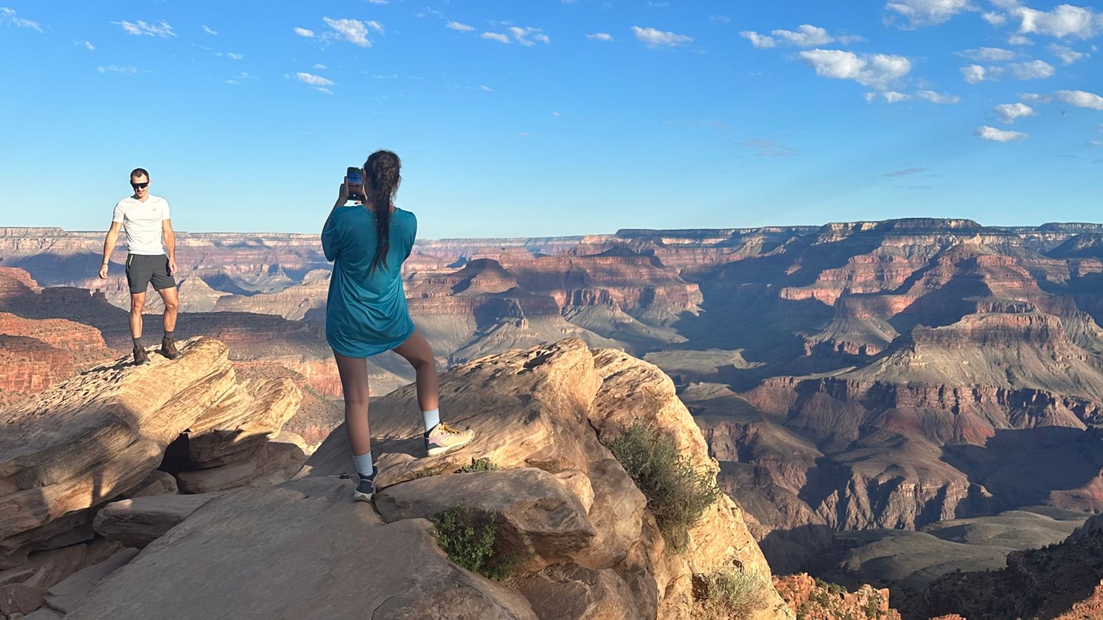 Two hikers take photos at the edge of the Grand Canyon on Grandview Trail