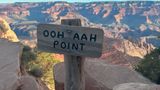 A wooden sign displayed in front of a stunning Grand Canyon viewpoint