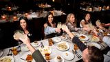 A foodie tour group cheers their drinks during a meal
