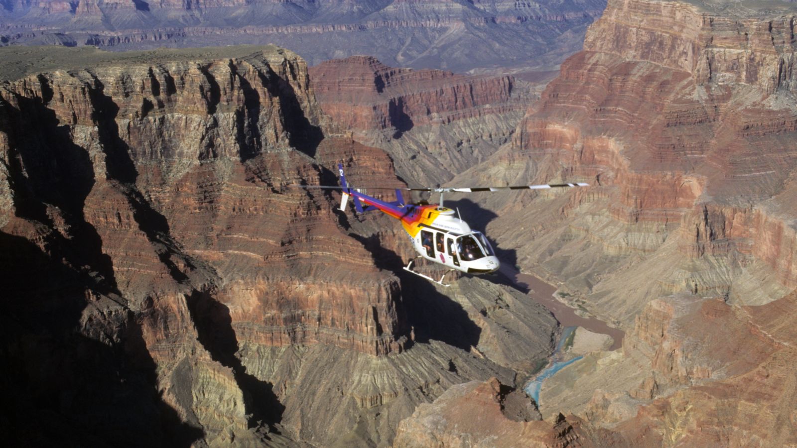 a rainbow helicopter flies over the Grand Canyon South Rim gorges