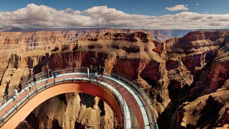 guests stand atop the Grand Canyon Skywalk with Eagle Point in the background