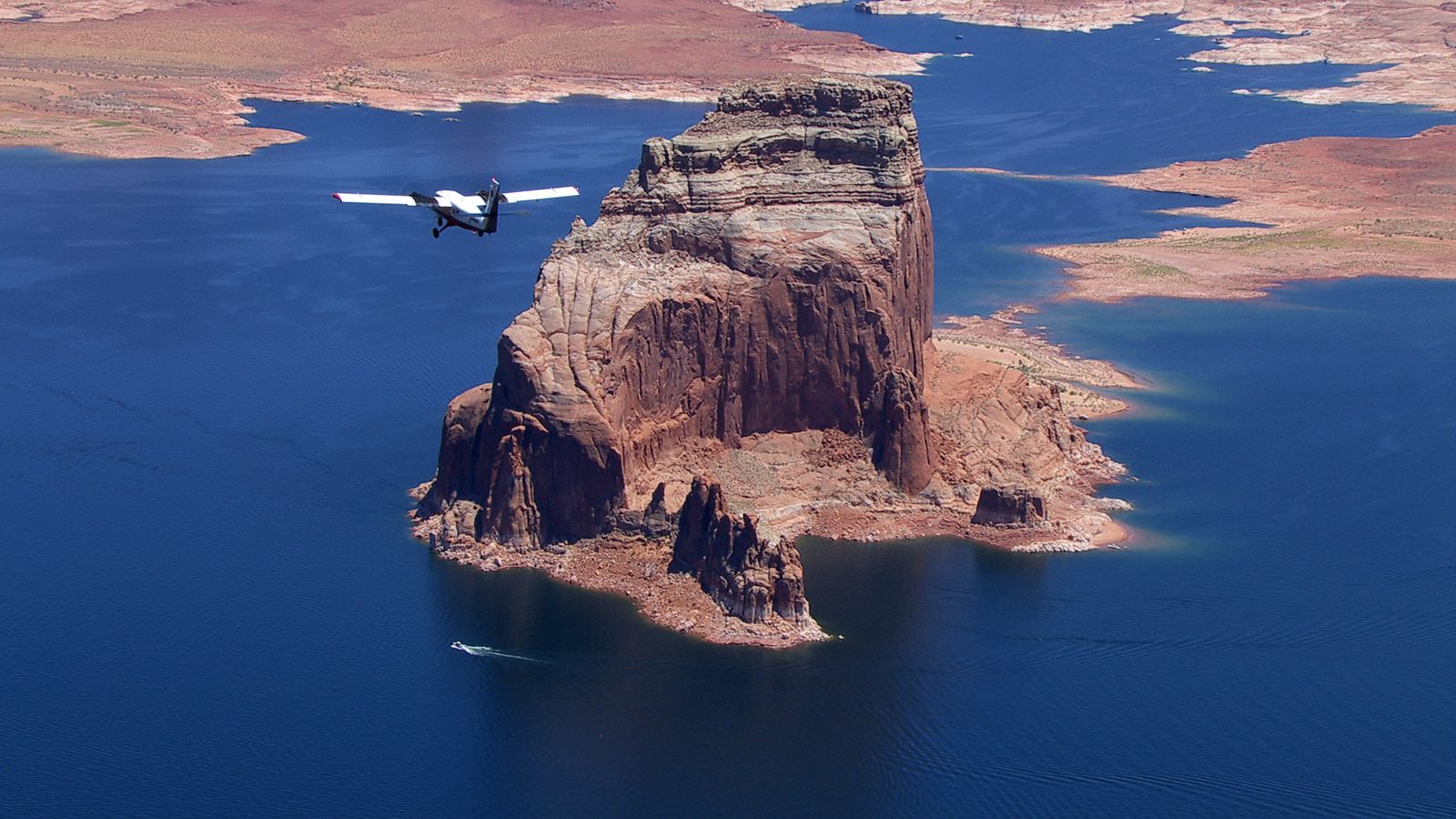 a touring airplane flies over lake powell and nearby canyons