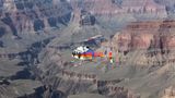A helicopter tour flies over unique and ancient rock formations across the canyon floor