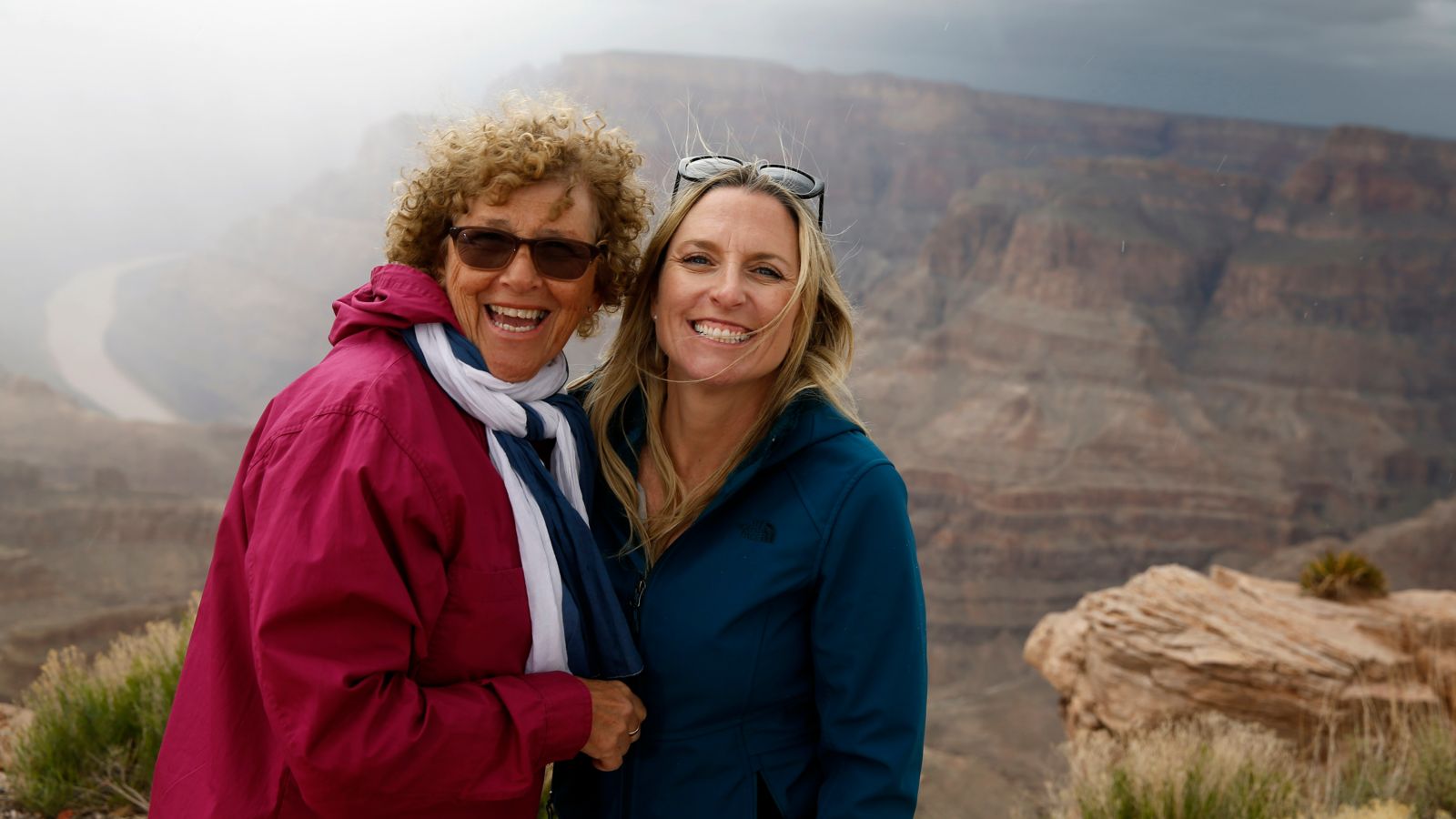Guests smiling at the camera with Grand Canyon West Guano Point in the background
