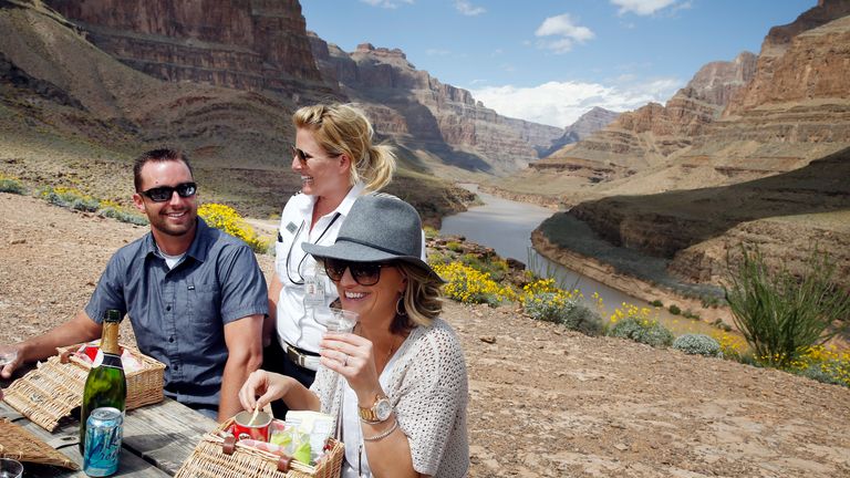 a couple enjoys lunch with their helicopter tour pilot on the floor of the Grand Canyon