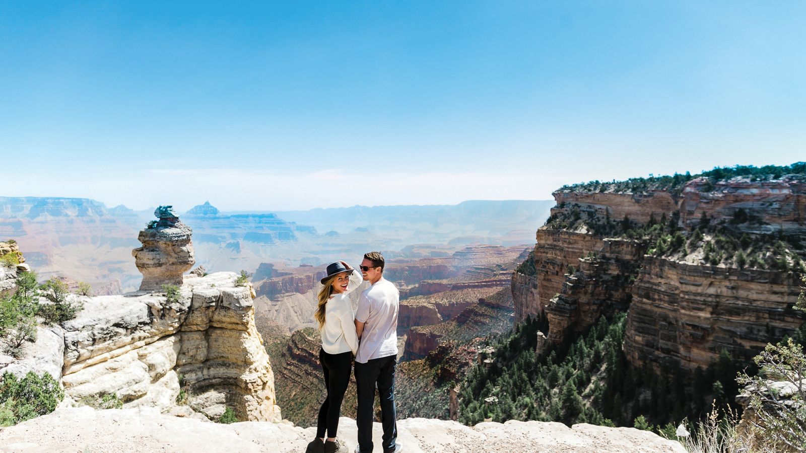 Couple holding hands standing near the edge of the Grand Canyon.