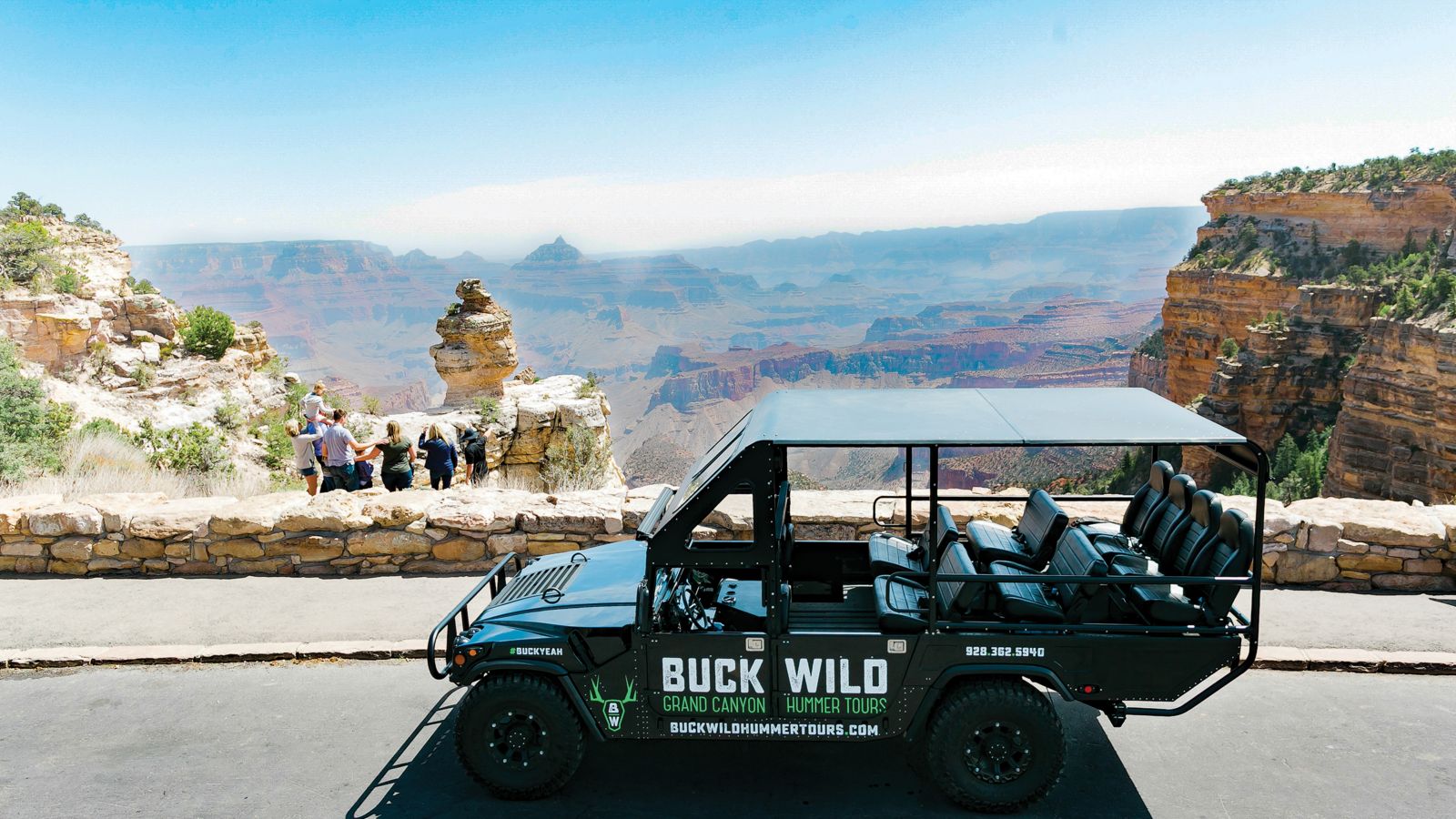 Family standing near the edge of the Grand Canyon with a Buck Wild Hummer in the foreground.