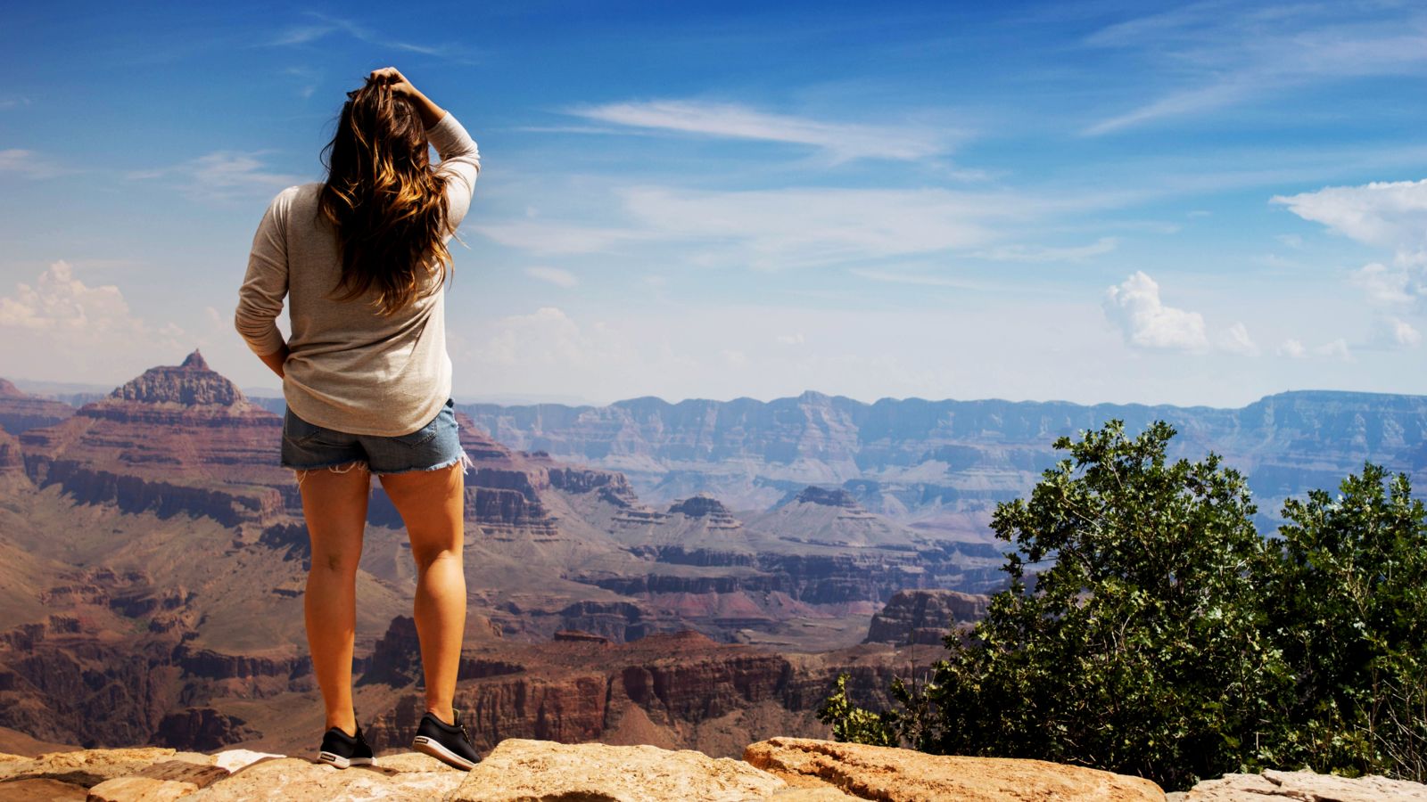 a woman stands at a grand canyon national park lookout point