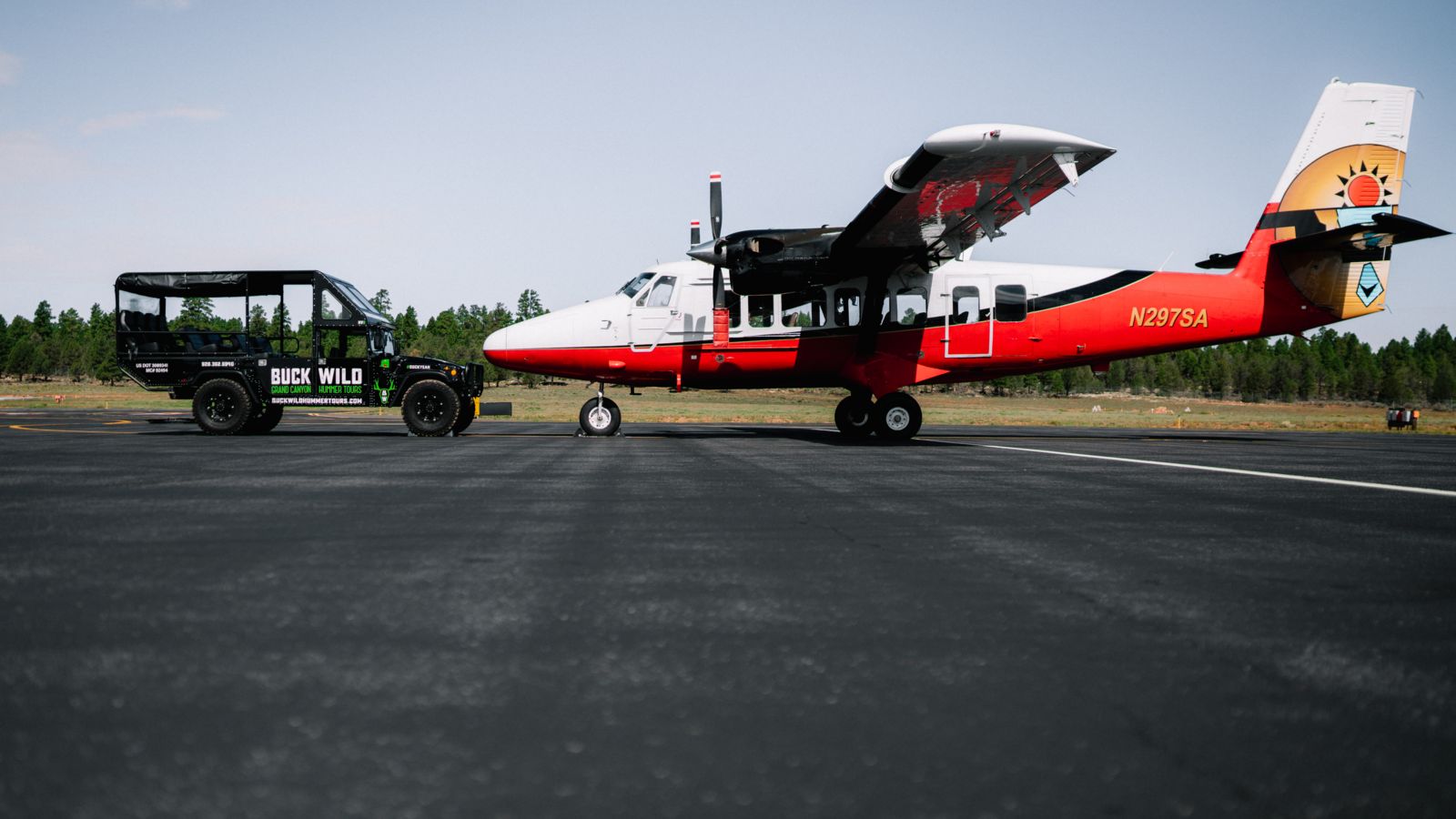 A Twin Otter airplane and a Buck Wild Hummer vehicle parked at Papillon's air terminal