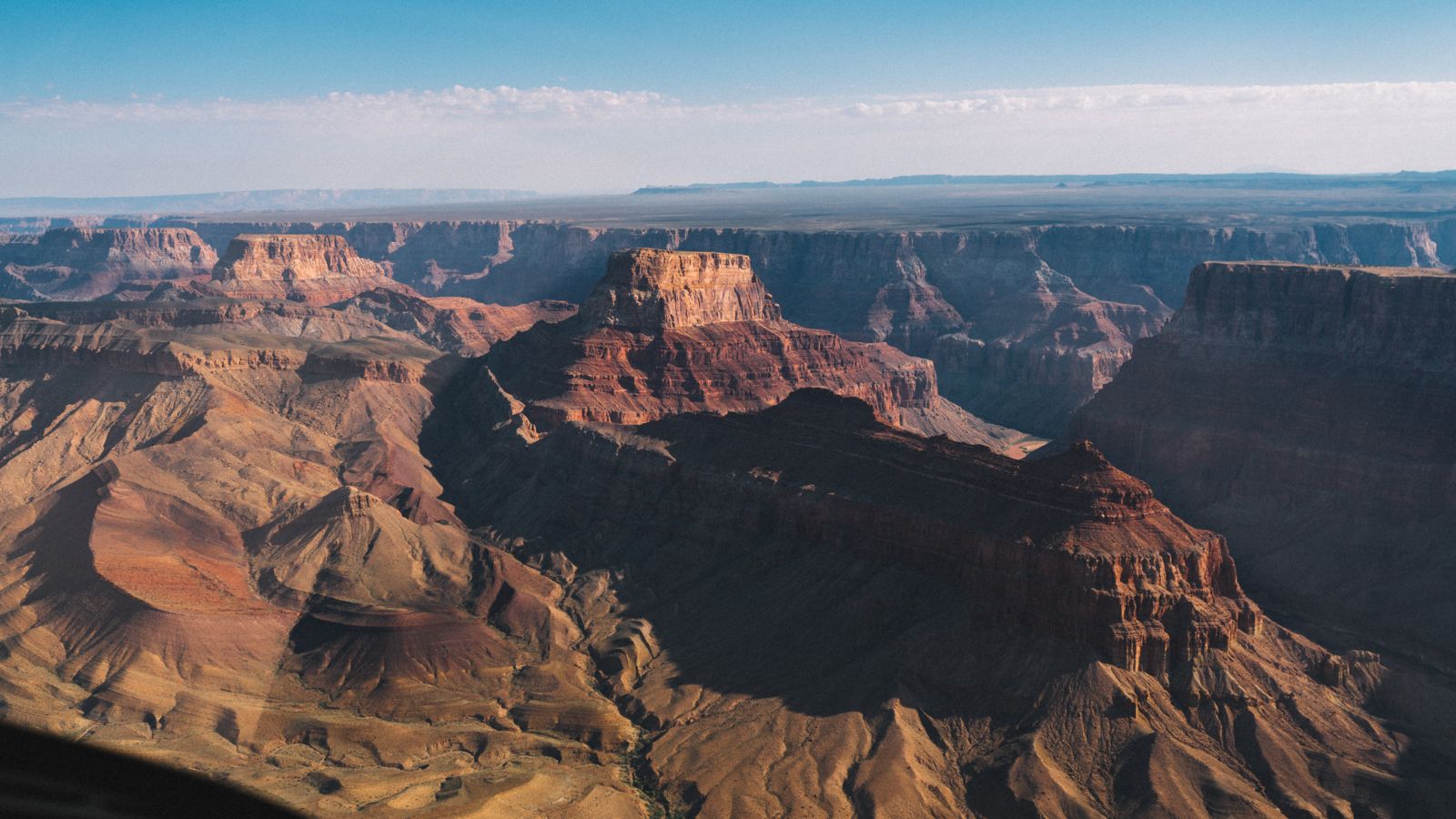 Shadows cast across bright red and orange walls of a section within the Grand Canyon South Rim