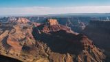 Shadows cast across bright red and orange walls of a section within the Grand Canyon South Rim