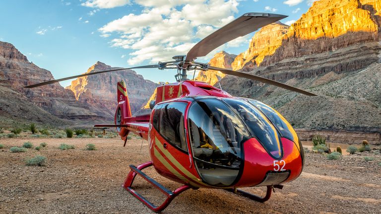 The Grand Canyon floor with a red helicopter landed in the foreground.