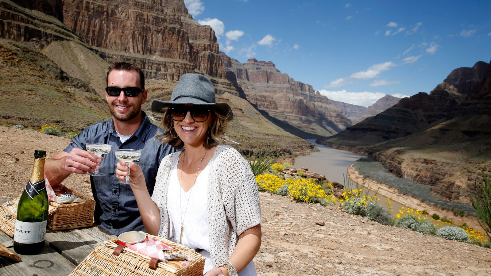 A man and woman toast champagne on the bottom of the Grand Canyon West.
