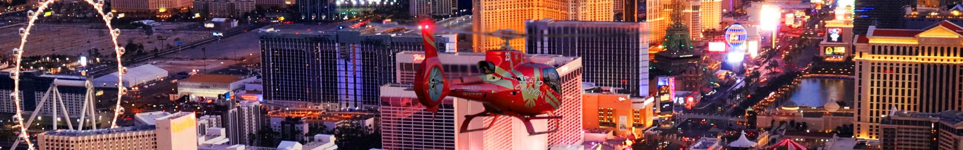 A red helicopter flying over the Las Vegas Strip near the High Roller