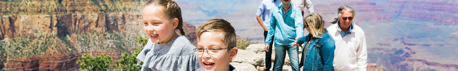 a family explores a Grand Canyon lookout point with two children in the foreground