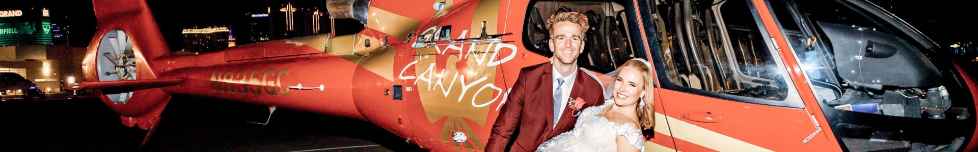 newlyweds pose in front a red helicopter on a tarmac by the Las Vegas Strip
