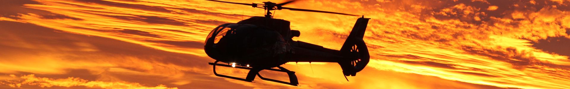 a grand canyon helicopter tour silhouetted against the bright orange sunset