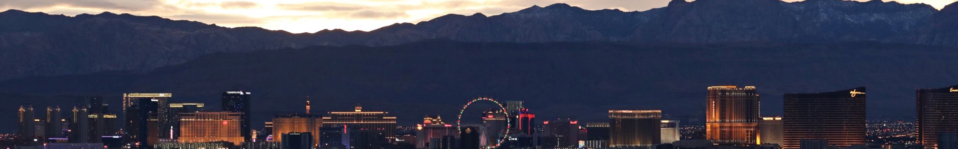 The Las Vegas Strip skyline seen illuminated against dark mountains in the background at sunset