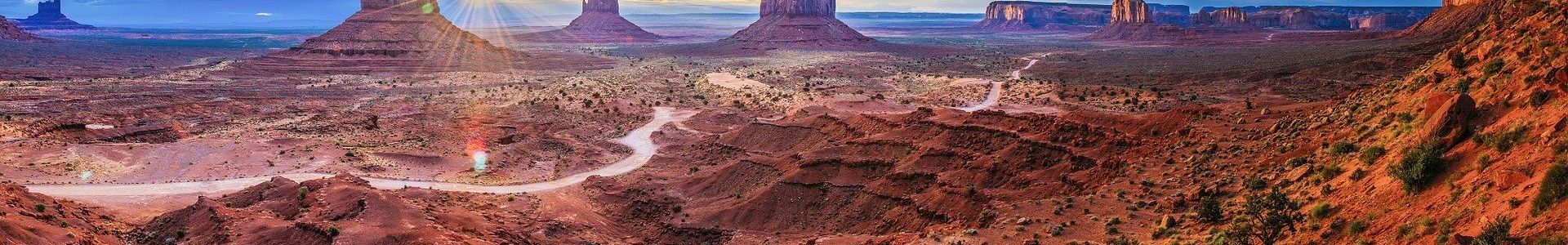 Monument Valley rock formations seen before a blue sky as the sun begins to set