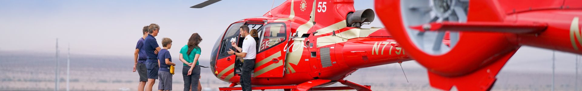 passengers board a red sightseeing helicopter on the tarmac at a Las Vegas air terminal