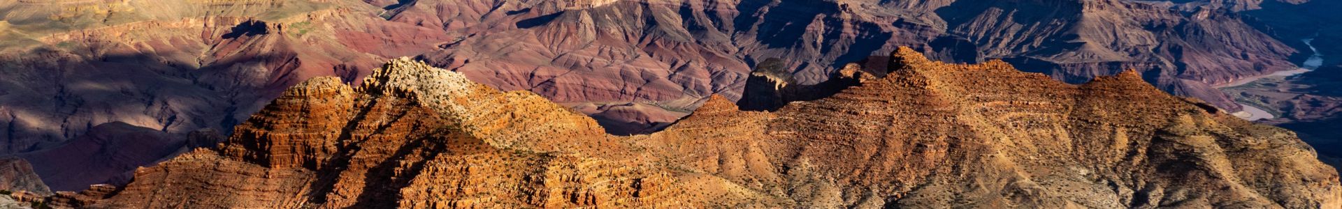 a Grand canyon landscape featuring a colossal sandstone wall illuminated by the desert sunset
