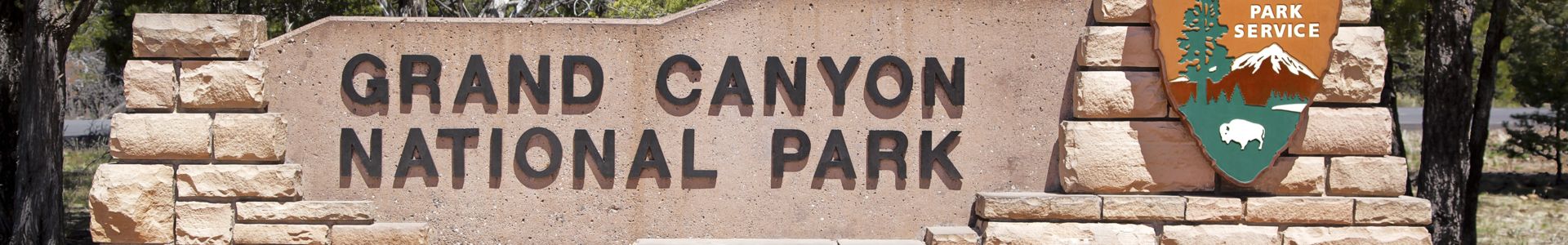 the entrance sign for the Grand Canyon National Park in bright sunlight