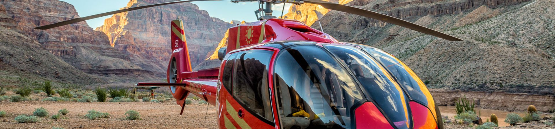 The Grand Canyon floor with a red helicopter landed in the foreground.