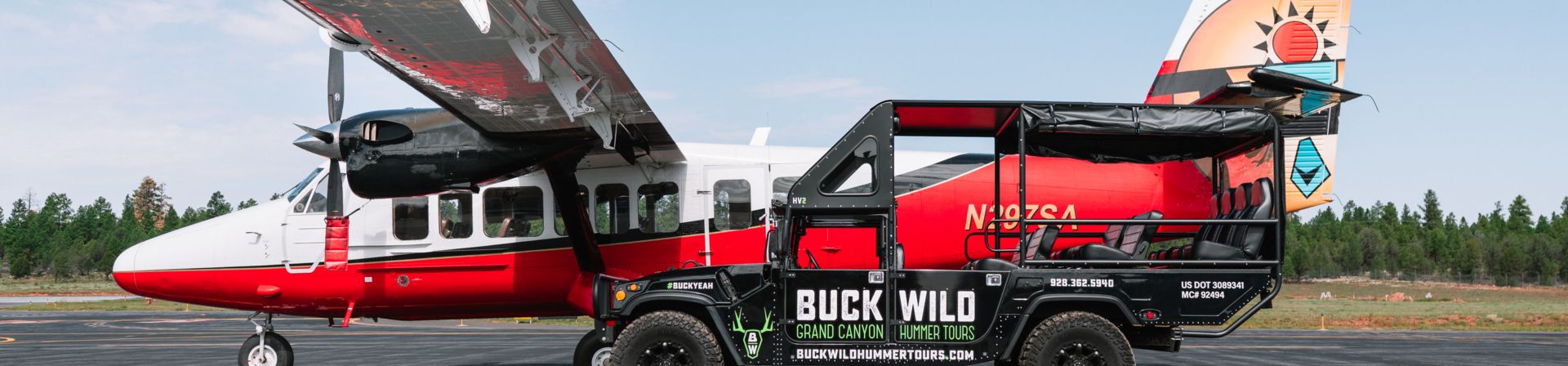 A side view of a Twin Otter airplane parked next to a Hummer vehicle