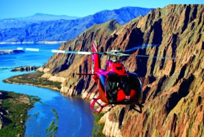 a helicopter tour flies over the las vegas desert and lake mead en route to the grand canyon west