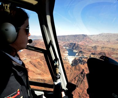 a red helicopter flies over Lake Mead from Las Vegas to the Grand Canyon West