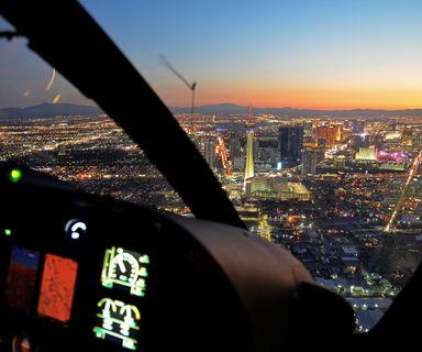 a Las Vegas helicopter tour flies toward the Stratosphere tower and casinos at sunset