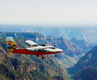 a touring airplane flies over the grand canyon south rim and its lush forestry
