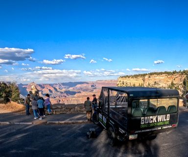 hummer tour passengers stand at a grand canyon national park lookout point