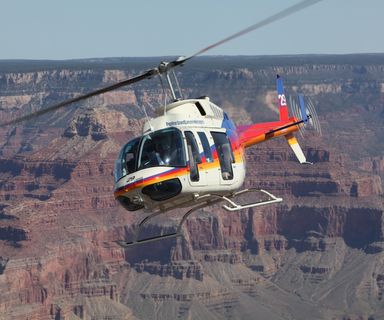 Papillon Grand Canyon Helicopters rainbow helicopter flying over the South Rim of Grand Canyon.