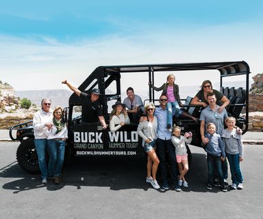 a rear view of a tour group standing at a grand canyon lookout point on a hummer tour