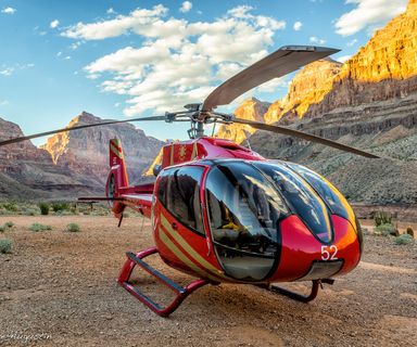 The Grand Canyon floor with a red helicopter landed in the foreground