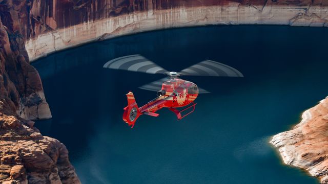Red helicopter flying over Glen Canyon Dam.