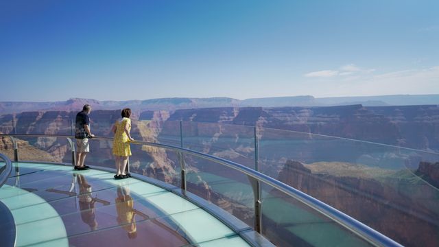 Two individuals looking out across Grand Canyon West landscape from the Skywalk Bridge.