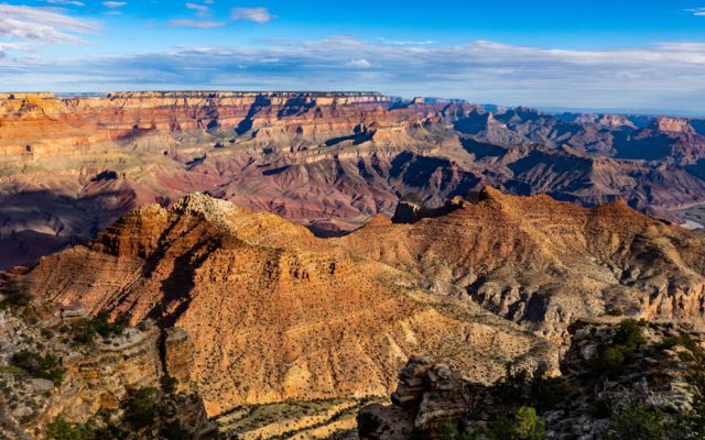 a Grand canyon landscape featuring a colossal sandstone wall illuminated by the desert sunset